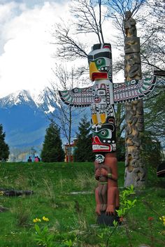 a wooden cross in the middle of a field with trees and mountains in the background