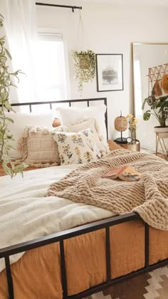 a bed with blankets and pillows on top of it in a room filled with plants