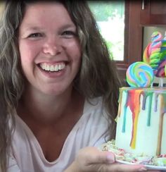 a woman is holding a cake with candy on it