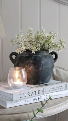 a vase with flowers on top of two books and a candle in front of it