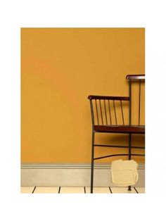 a chair sitting in front of a yellow wall