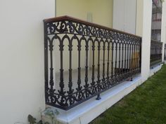 an iron balcony railing on the side of a building with grass in front of it