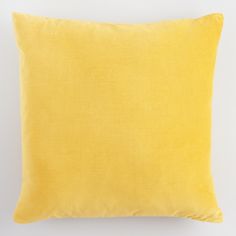 a yellow pillow sitting on top of a white wall