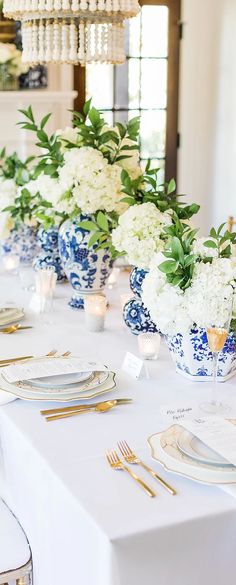 there are many blue and white vases on the table with gold place settings in front of them