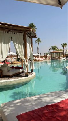 an outdoor swimming pool with cabanas and lounge chairs