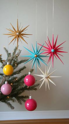 three christmas ornaments hanging from the ceiling next to a tree