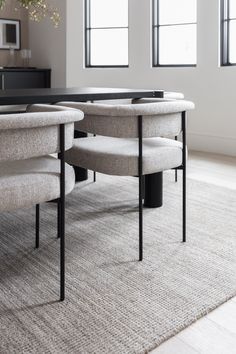 a dining table with four chairs in front of it and two vases on the other side