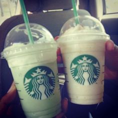 two starbucks drinks are being held in their hands