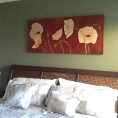 a bed with white pillows and a painting on the wall above it in a bedroom