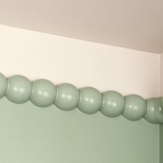 there is a green wall with some balloons hanging on the top and bottom half of it