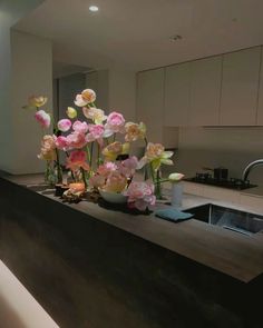 a kitchen counter with flowers on it and a sink in the backgrouund