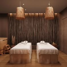 two beds in a room with wooden walls and lamps hanging from the ceiling above them