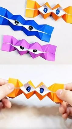 two hands holding origami pieces with eyes on them