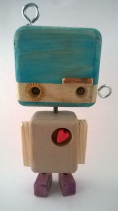 a small wooden toy with a blue and brown box on it's head, holding a red heart