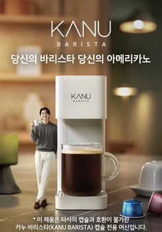 a man standing next to a coffee cup on top of a counter with the words kanu barista written in korean