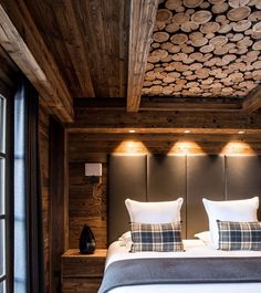 a bed in a room with wooden walls and wood flooring on the ceiling is lit by two lights