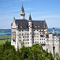 a large castle with many towers on top of it's sides surrounded by trees