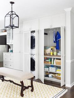 a laundry room with white cabinets and shelves filled with washer and dryer items