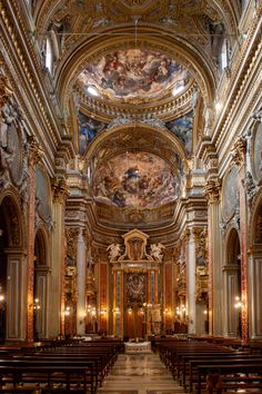 the inside of a church with many pews and paintings on the walls above them