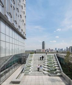 people are walking up and down the stairs in front of a tall building with glass windows