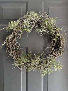 a wreath made out of twigs and branches hanging on the front door to hang it