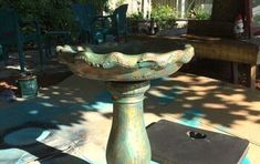 a bird bath sitting on top of a cement slab