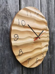 a wooden clock on the side of a fence with numbers painted on it's face