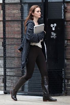 a woman is walking down the street with her tablet computer in her hand and she's wearing black boots