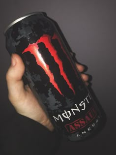 a hand holding a can of monster energy drink