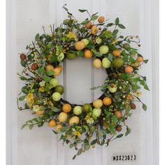 a wreath with oranges and green leaves on a white door frame hanging on a wall