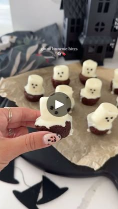 someone is holding up some cupcakes with white frosting and black bears on them