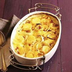 a casserole dish with potatoes in it on a table next to silverware