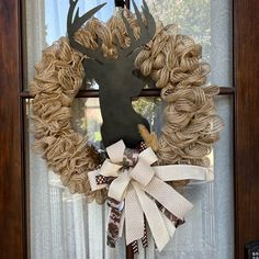 a wreath with a deer head on it is hanging in front of a door window