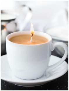 a cup of coffee with a lit candle in it on a saucer and plate