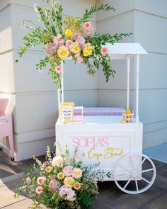 an ice cream cart decorated with flowers and greenery for a baby's first birthday