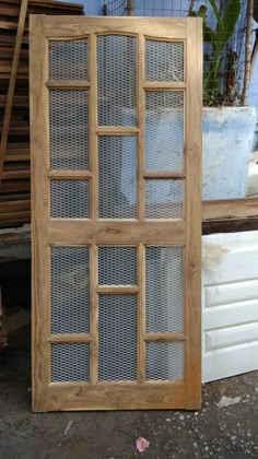 a wooden window sitting next to a pile of wood planks on top of a floor