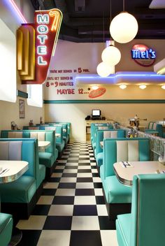 the interior of a diner with checkered flooring and neon signs hanging from the ceiling