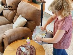 a woman is using a vacuum cleaner on the floor in front of a brown couch