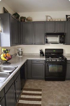 a kitchen with gray cabinets and marble counter tops, stainless steel appliances and an area rug