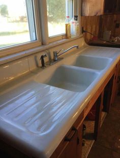 a kitchen with two sinks and a window in the back ground, next to a counter