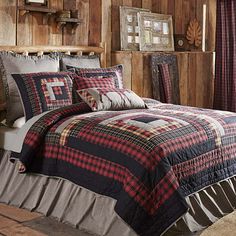 a bed in a room with wooden walls and plaid bedspread on the bed