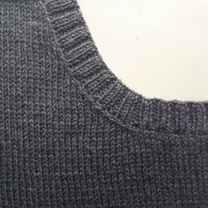 a close up view of the back of a knitted sweater that is partially finished