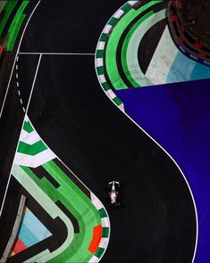 an aerial view of a motorcycle driving on a race track with multiple colors and curves