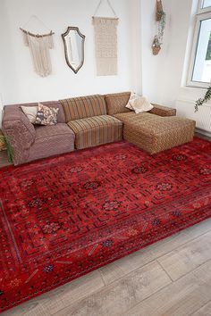 a living room with a large red rug in front of a couch and mirror on the wall