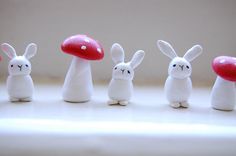 several small white rabbits with red mushrooms on their heads and legs, standing in front of each other