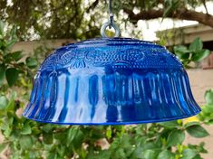 a blue bird feeder hanging from a tree