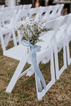 white folding chairs with blue ribbon tied around the back and flowers in vases sitting on them