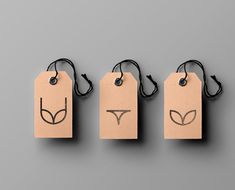 three tags with faces drawn on them hang from black string against a gray background,