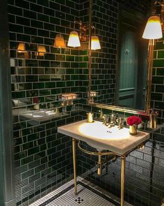 a bathroom with green tiled walls and white sink in the center, surrounded by gold fixtures