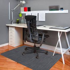 an office chair sitting on top of a hard wood floor next to a white desk